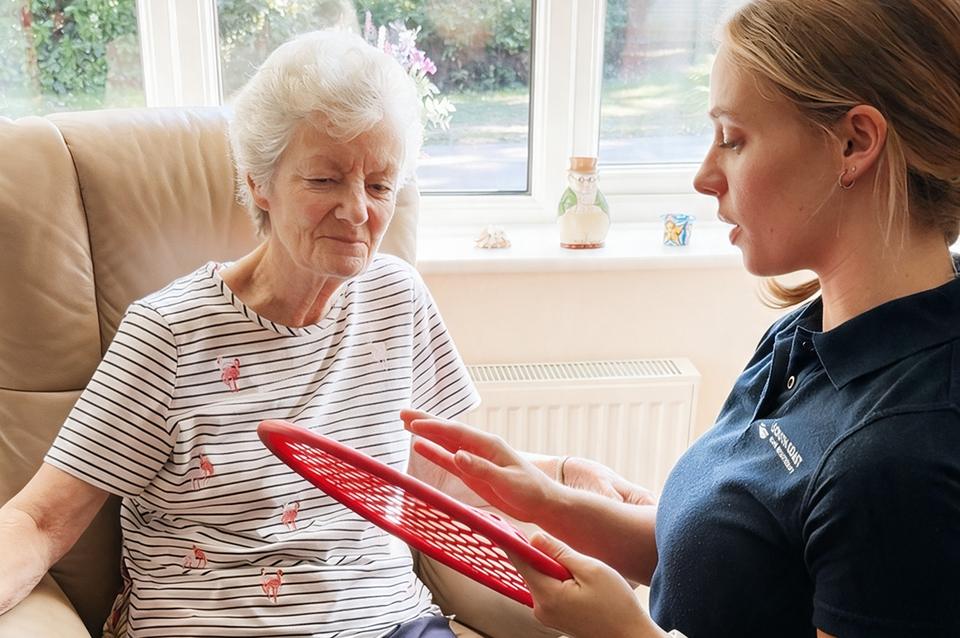 A physiotherapist demonstrating a hand exercise board at home